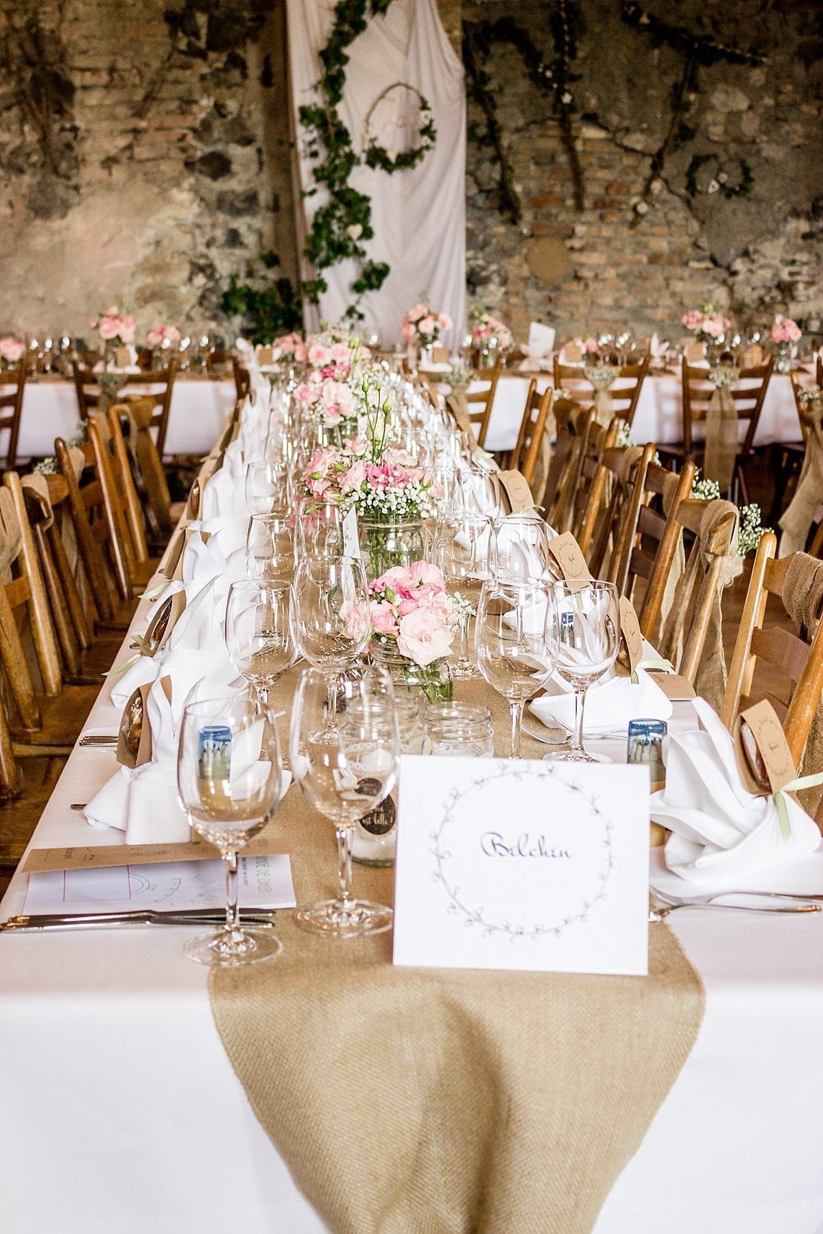 Hochzeitlich gedeckte Tische die mit Blumen geschmückt sind.