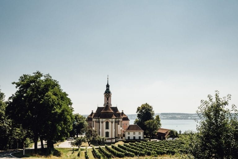 Ein idyllisches Bild einer Kirche vor dem Panorama des Bodensees.
